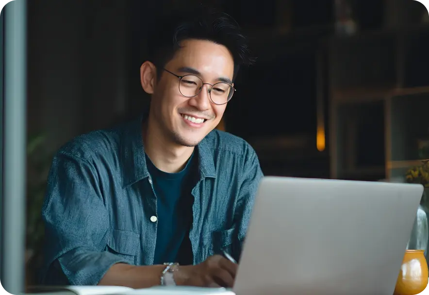A man smiles as he looks at his laptop computer.