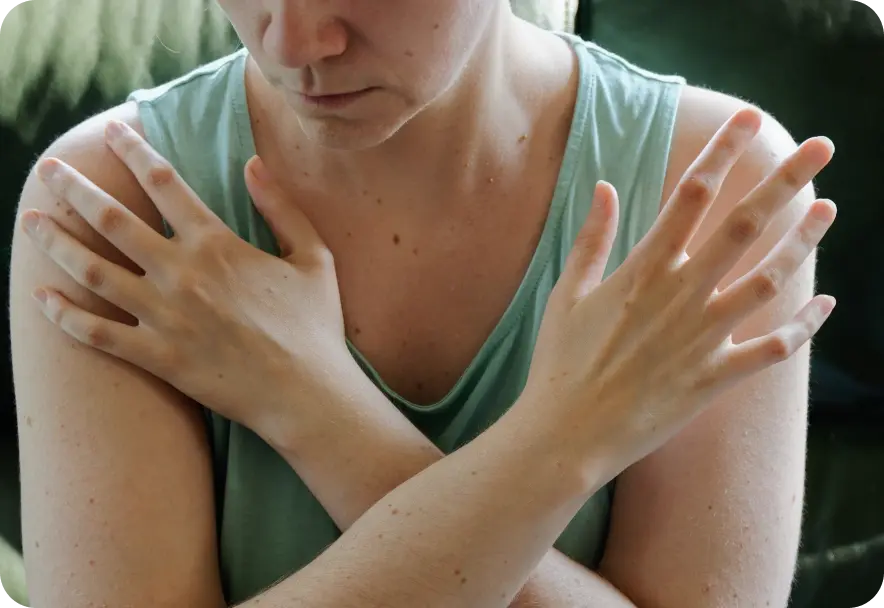 A person makes an x shape with their arms while placing their hand son opposite shoulders